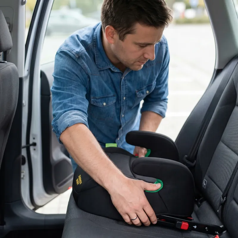 Driver installing a certified booster seat on the back seat of an airport taxi